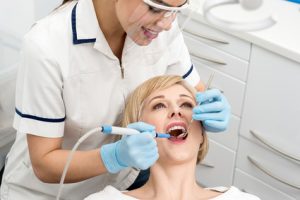Female dentist inspecting teeth of patient
